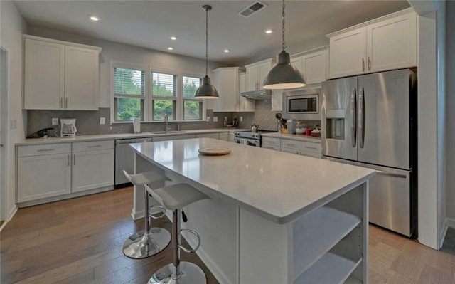 6003 Rollingwood Way, Hoschton, GA 30548 - kitchen with stainless steel appliances, open shelves, white cabinetry, under cabinet range hood, and light countertops