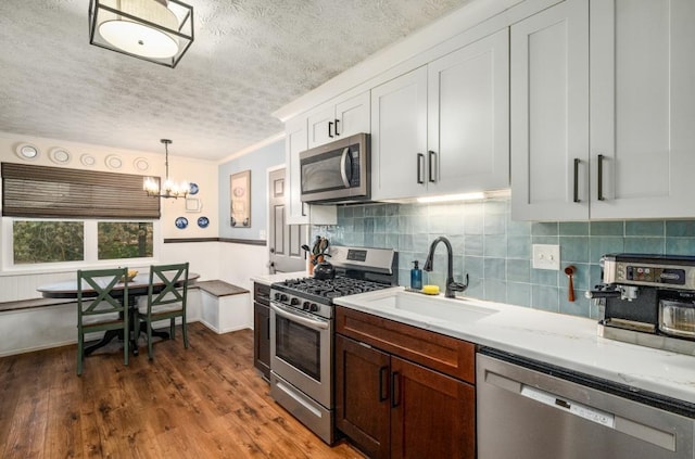 kitchen featuring stainless steel appliances, sink, decorative light fixtures, white cabinets, and an inviting chandelier