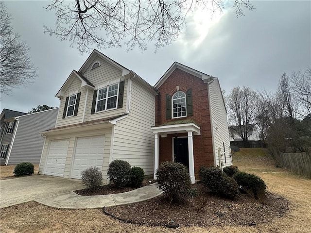 traditional home featuring brick siding, an attached garage, concrete driveway, and fence