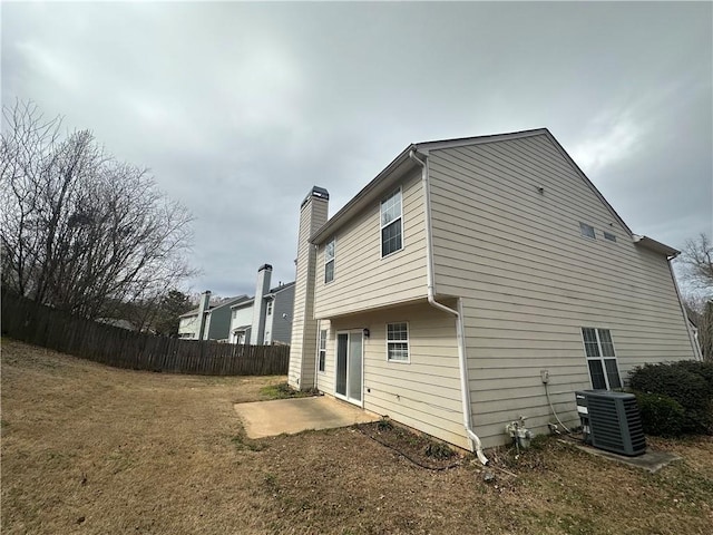 rear view of property featuring central air condition unit, a patio area, a chimney, and fence