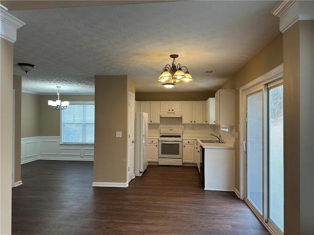 kitchen featuring white appliances, visible vents, a sink, under cabinet range hood, and a notable chandelier