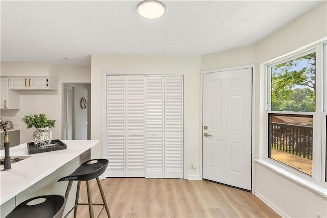 5759 Albans Way, Lithonia, GA 30058 - kitchen featuring light wood-type flooring, light countertops, a kitchen breakfast bar, baseboards, and white cabinetry