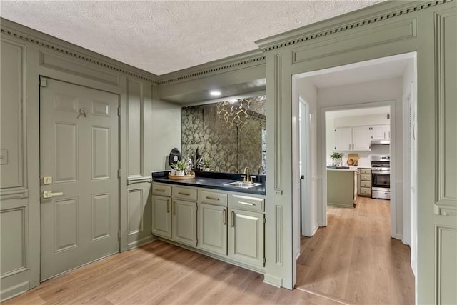 5759 Albans Way, Lithonia, GA 30058 - bar area featuring stainless steel gas range, light wood finished floors, a sink, under cabinet range hood, and a textured ceiling
