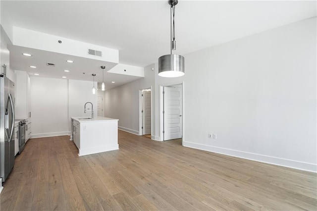 kitchen with stove, baseboards, a sink, light wood finished floors, and visible vents