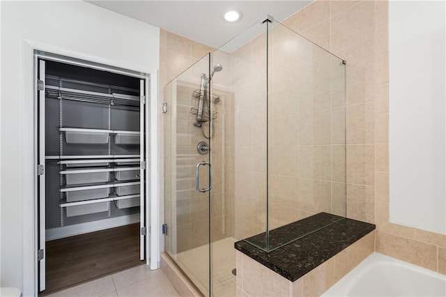 bathroom featuring a spacious closet, tile patterned flooring, a stall shower, and recessed lighting