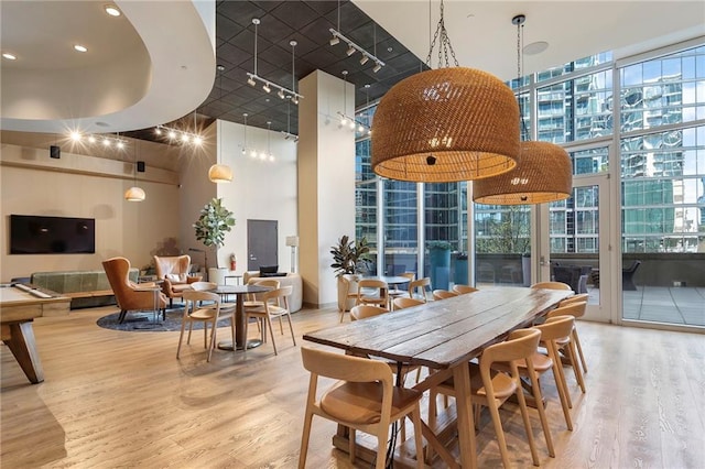 dining space featuring a high ceiling, a wall of windows, and wood finished floors