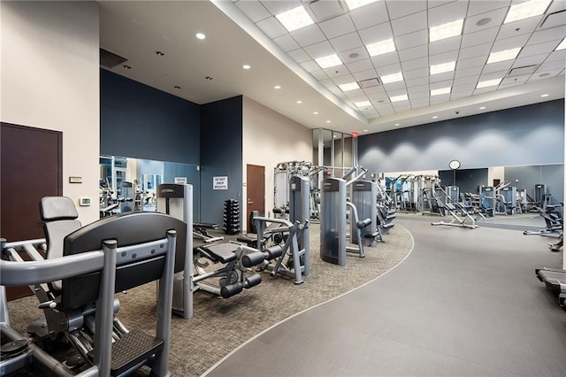 exercise room featuring a towering ceiling, a drop ceiling, and recessed lighting