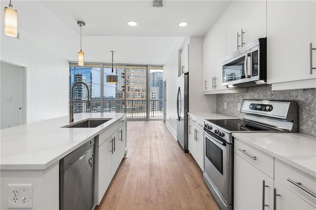 kitchen featuring a sink, white cabinetry, tasteful backsplash, appliances with stainless steel finishes, and light wood-type flooring