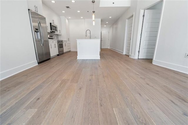 kitchen with white cabinetry, open floor plan, light wood-style floors, and appliances with stainless steel finishes