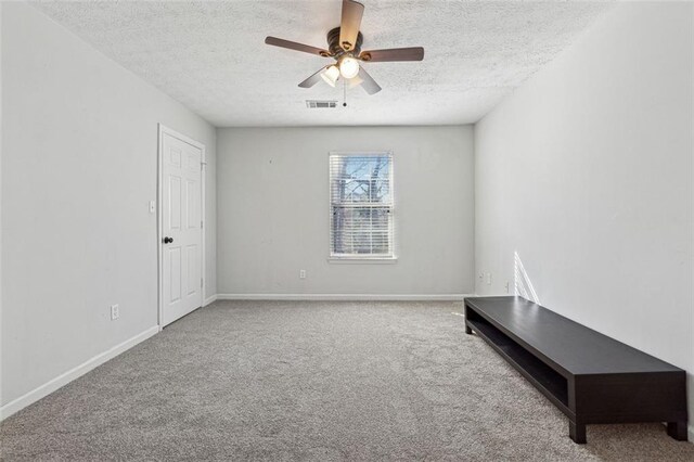 carpeted spare room with ceiling fan and a textured ceiling