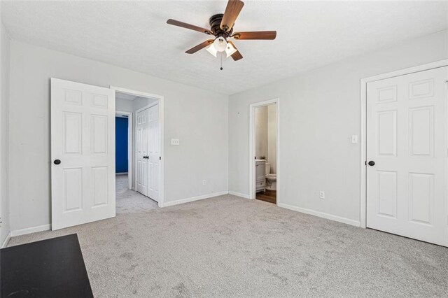 unfurnished bedroom with light carpet, ceiling fan, and ensuite bath