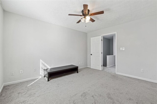 unfurnished bedroom featuring a textured ceiling, light colored carpet, and ceiling fan