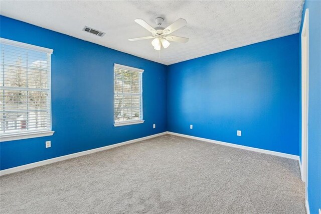 unfurnished room featuring ceiling fan, a textured ceiling, and carpet