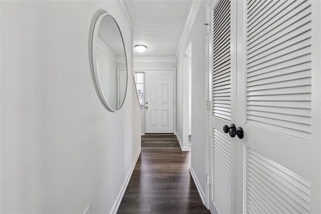 corridor with dark wood-type flooring, ornamental molding, and a textured ceiling