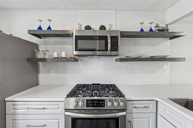 kitchen with stainless steel appliances, white cabinets, and a textured ceiling