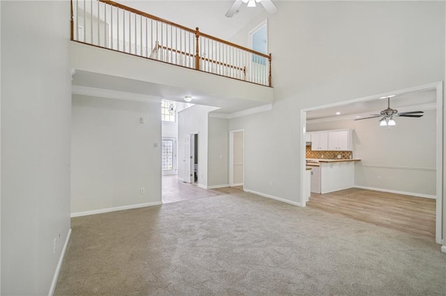 unfurnished living room featuring baseboards, a ceiling fan, and light colored carpet