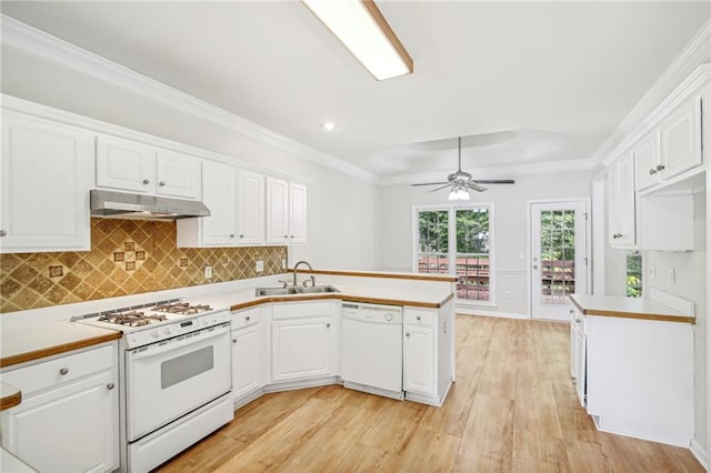 kitchen with white appliances, a peninsula, under cabinet range hood, white cabinetry, and a sink