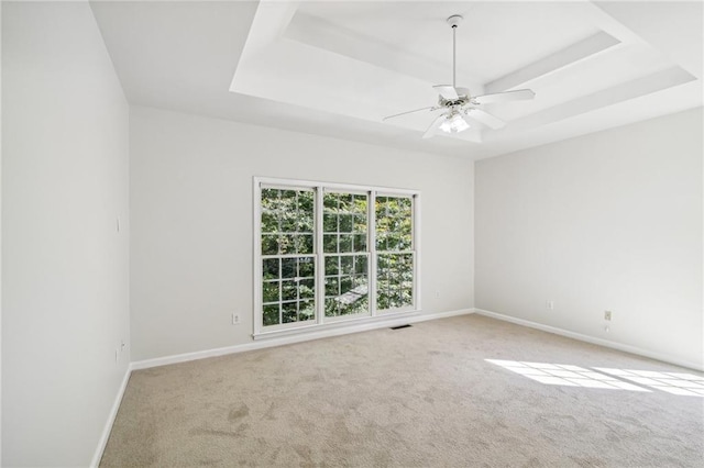 spare room featuring visible vents, a tray ceiling, baseboards, and light colored carpet