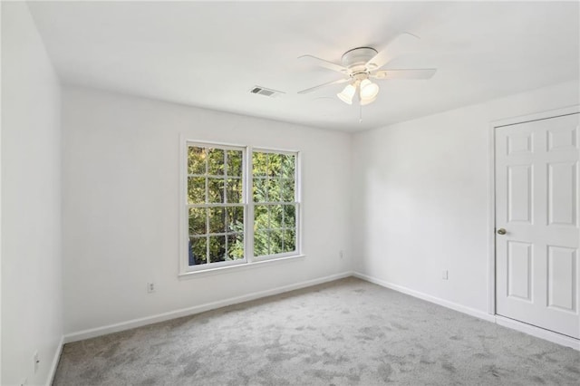 carpeted empty room with visible vents, ceiling fan, and baseboards