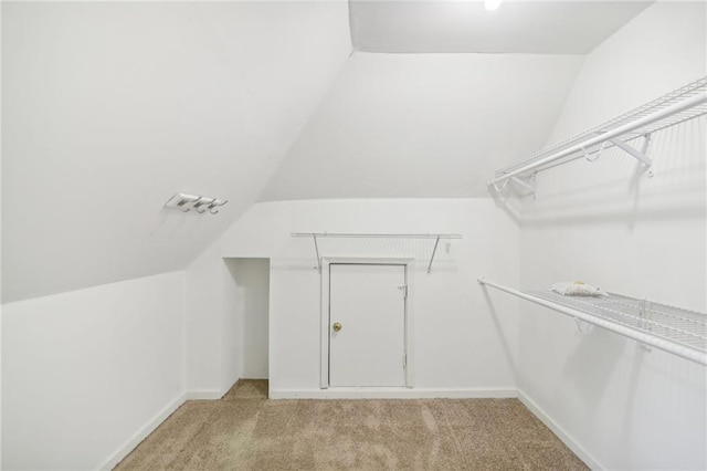 walk in closet with lofted ceiling and light colored carpet