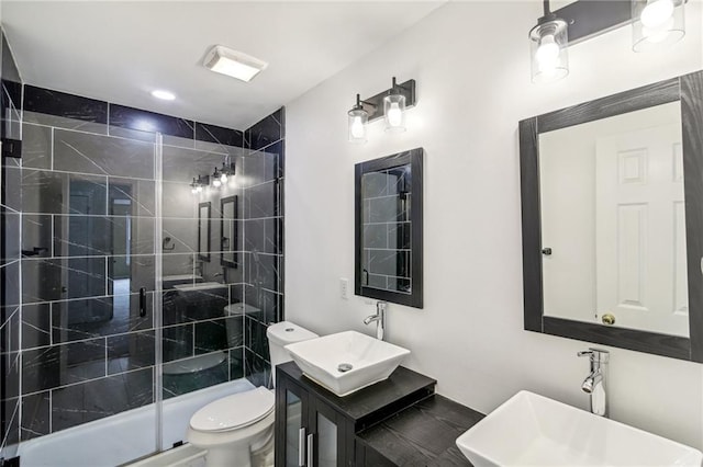 full bath with double vanity, a sink, toilet, and a shower stall