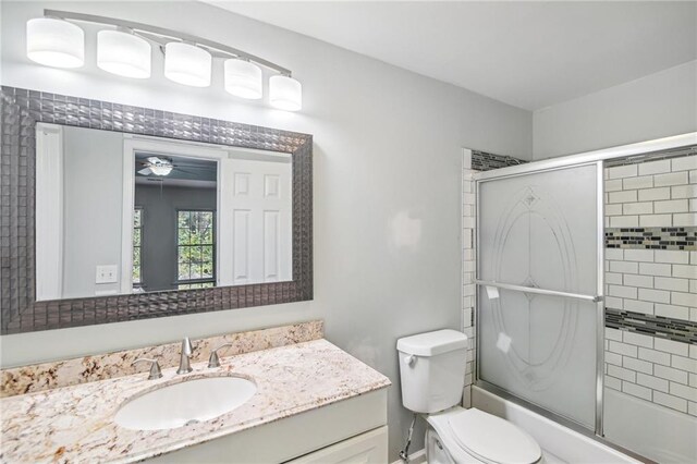 full bath featuring toilet, combined bath / shower with glass door, and vanity