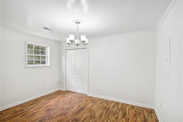 empty room featuring baseboards, visible vents, wood finished floors, crown molding, and a chandelier