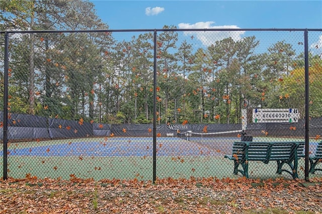 view of tennis court featuring community basketball court and fence