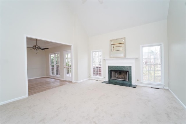 unfurnished living room with high vaulted ceiling, a premium fireplace, carpet flooring, and a wealth of natural light