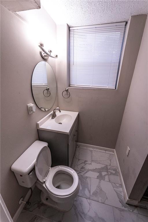 bathroom with a textured ceiling, vanity, and toilet