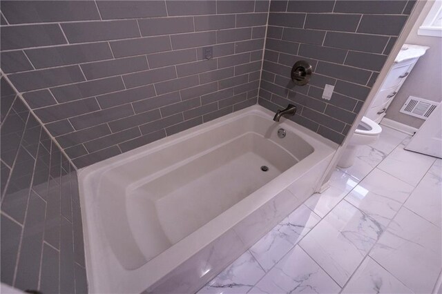 bathroom with tiled shower / bath combo and toilet