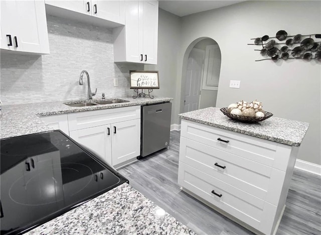 3046 Dobbs Way, East Point, GA 30344 - kitchen featuring stainless steel dishwasher, a sink, arched walkways, backsplash, and light wood-style floors