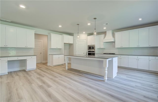 18 Slick Ct, Senoia, GA 30276 - kitchen featuring custom exhaust hood, appliances with stainless steel finishes, decorative backsplash, recessed lighting, and light wood-style flooring