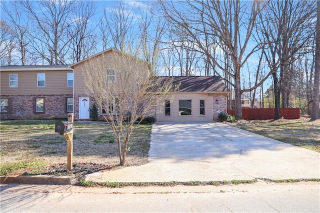 view of front of home with driveway, fence, and brick siding