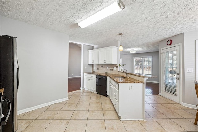 kitchen featuring decorative light fixtures, dishwasher, kitchen peninsula, stainless steel refrigerator, and white cabinetry