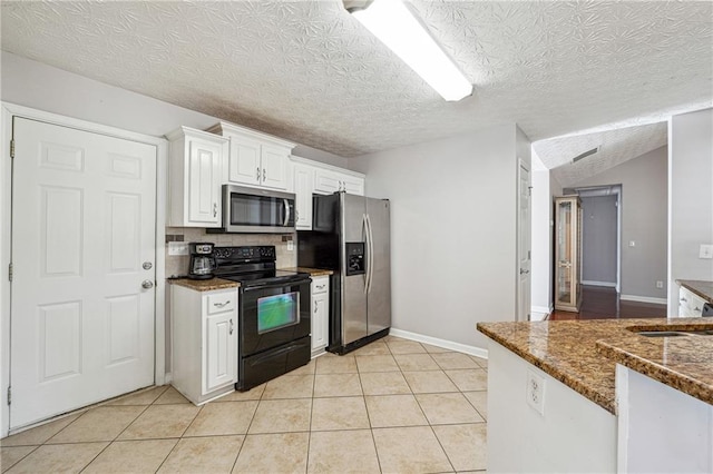 kitchen with white cabinets, appliances with stainless steel finishes, dark stone countertops, sink, and light tile patterned floors