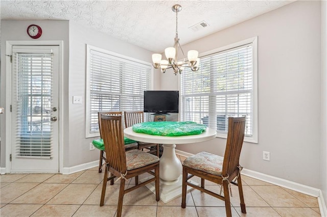 tiled dining room with a notable chandelier and a textured ceiling