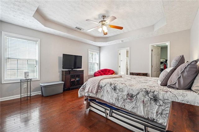 bedroom with ceiling fan, multiple windows, a textured ceiling, and a raised ceiling