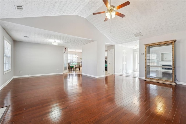 unfurnished living room with vaulted ceiling, dark wood-type flooring, a textured ceiling, and ceiling fan with notable chandelier