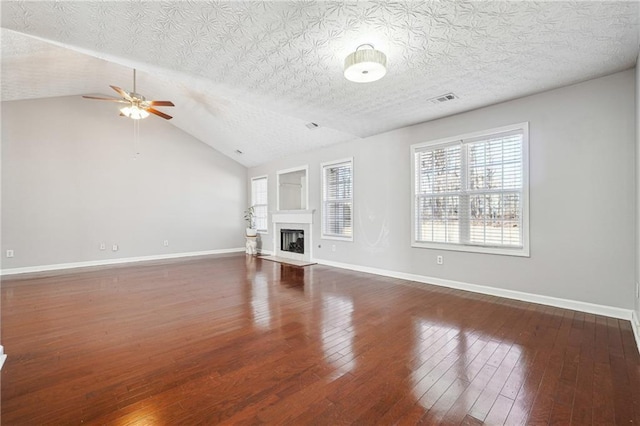 unfurnished living room featuring lofted ceiling, ceiling fan, dark hardwood / wood-style flooring, and a textured ceiling