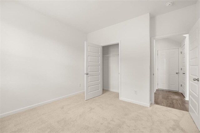 unfurnished bedroom with light colored carpet and a closet