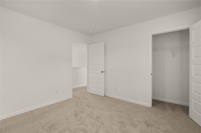 unfurnished bedroom with light colored carpet and a closet