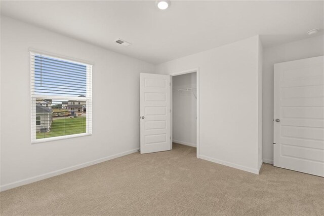 unfurnished bedroom with light colored carpet and a closet