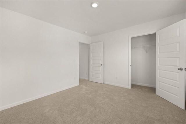 unfurnished bedroom with light carpet and a closet