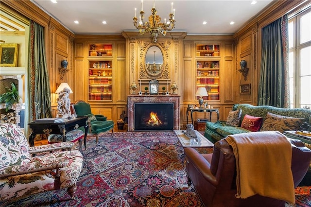 living area with ornamental molding, a chandelier, and built in shelves