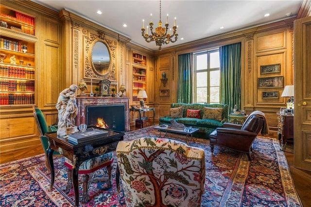 living area featuring a notable chandelier, hardwood / wood-style flooring, built in features, and ornamental molding