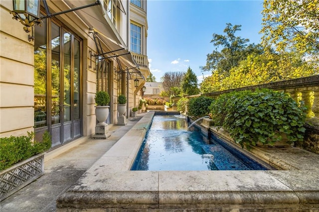 view of pool with pool water feature and a patio area