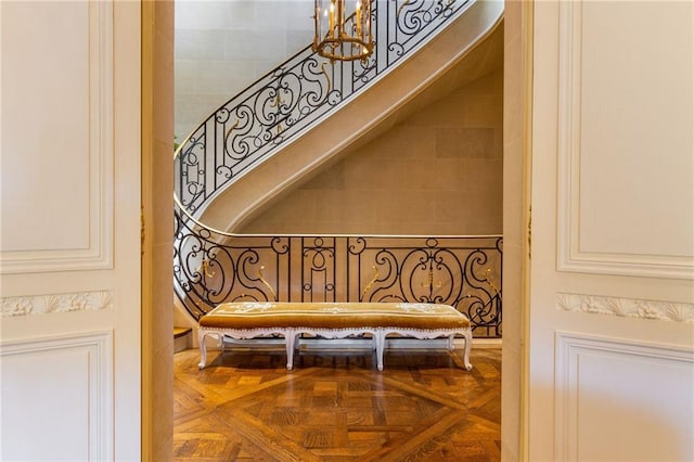 stairs with an inviting chandelier and parquet floors