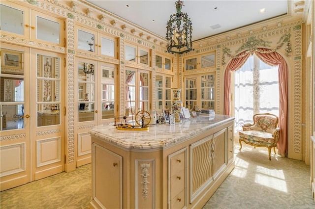 kitchen featuring light stone counters, a center island, and a notable chandelier