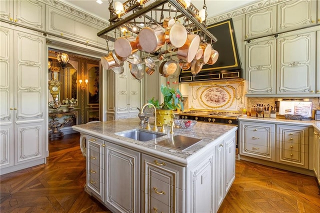 kitchen featuring sink, a kitchen island with sink, crown molding, and dark parquet flooring